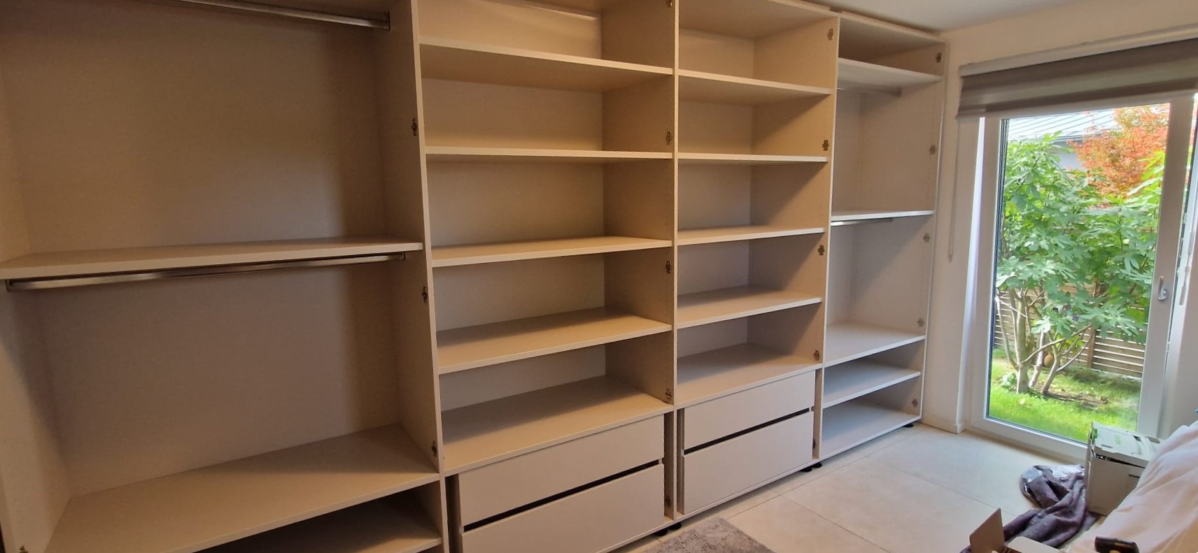 Ankleide-Einbauschrank in Nürnberg vor dem Einbau der Türen: 4 Schubladen (später hinter den Türen versteckt), 4 Kleiderstangen und viele Regale.