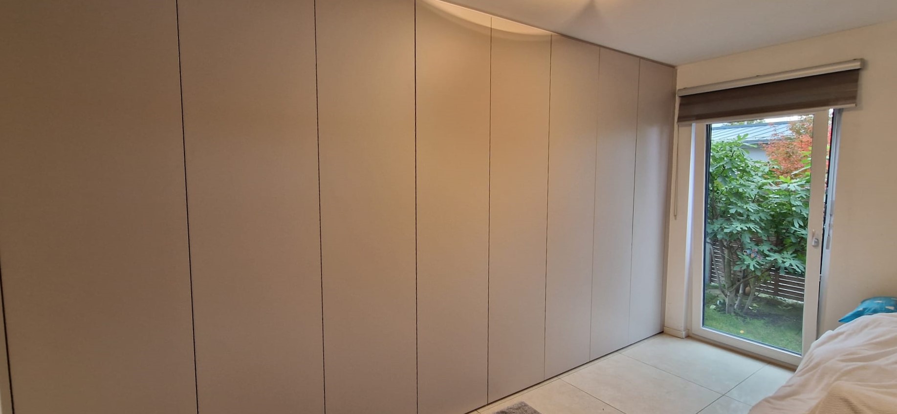 Ankleidezimmer-Schrank nach Maß: Mit Kaschmir-grauen, bis zur Decke gehenden Türen verschwendet der Einbauschrank in der Ankleide keinen Platz und füllt die gesamte Wand.