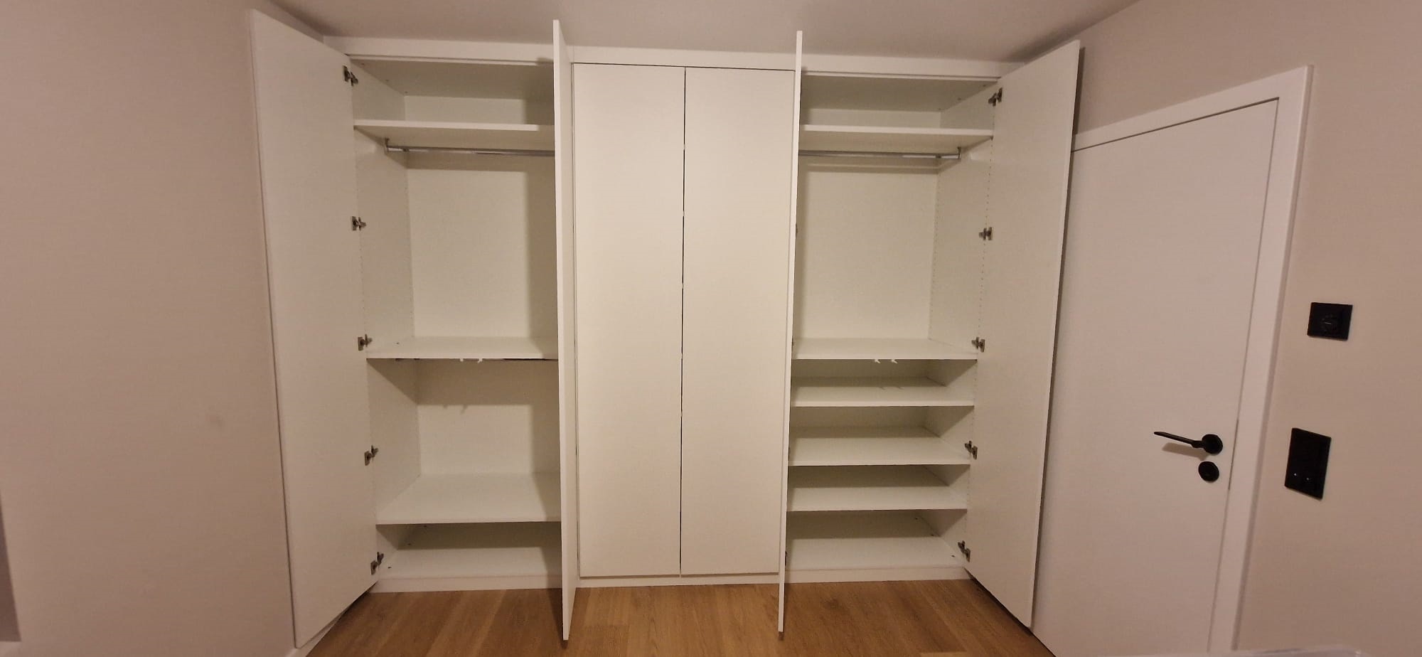 Weißer Einbauschrank Kinderzimmer: Die rechten und linken Türen sind geöffnet und zeigen mehrere Einlegeböden und 3 Kleiderstangen.