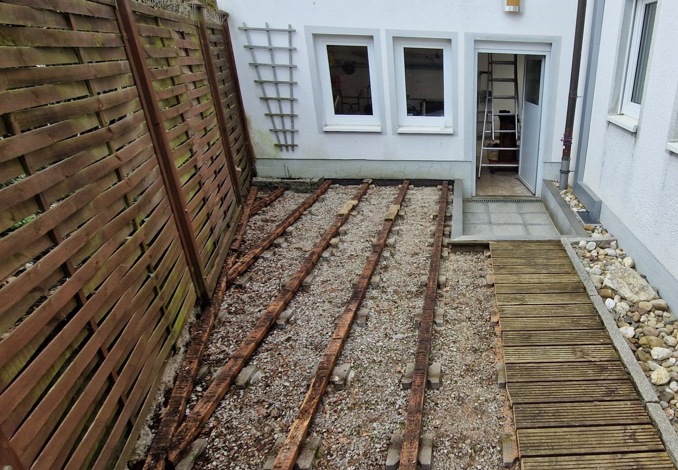 Vor der Terrassensanierung: Vermoderter Unterbau der Holzterrasse und vermooster Sichtschutz.